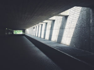 A dark pathway underground with several spaces allowing light in